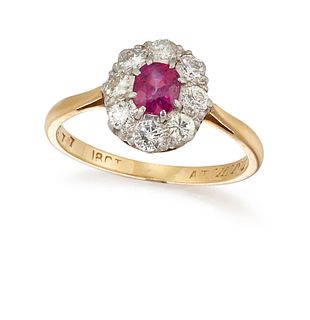 A RUBY AND DIAMOND CLUSTER RING, the oval cut ruby set within a surround of