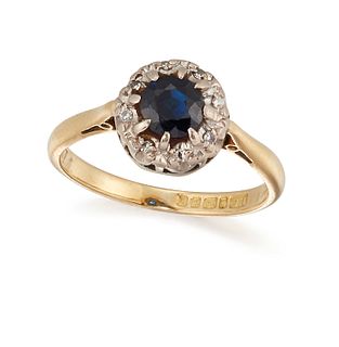 A SAPPHIRE AND DIAMOND RING, the round cut sapphire set within a subtle sur