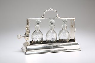 AN EDWARDIAN SILVER-PLATED THREE-BOTTLE TANTALUS, the locking mechanism com