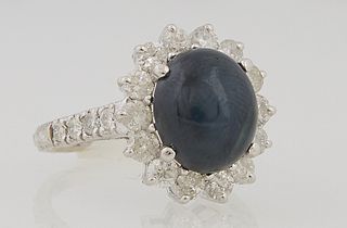 Lady's 14K White Gold Dinner Ring, with a 5.23 carat oval cabochon star sapphire, atop a border of round diamond mounted "points," t...