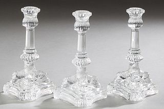 Set of Three Tiffany & Co. Molded Crystal Candlesticks, 20th c., the candle cup on a flaring octagonal support, on tripodal dolphin...
