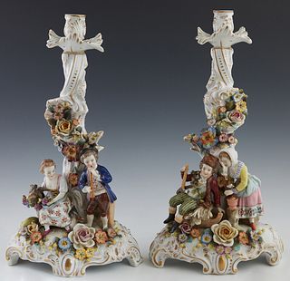 Pair of Meissen Style Porcelain Candlesticks, late 19th/early 20th c., encrusted with flowers, one with a musician and a farmer woman with a goat; the
