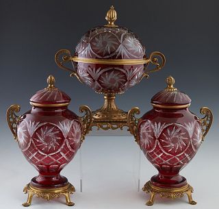 Three Piece Ruby Cut-to-Clear Glass and Brass Garnitures, 20th c., consisting of a large covered handled circular bowl on a brass socle support on fou
