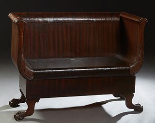American Carved Mahogany Hall Bench, c. 1900, with a high back and scrolling leaf carved arms, above a seat with a lifting storage compartment, the wh