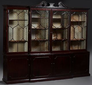 English Victorian Carved Mahogany Breakfront Bookcase, 19th c., with a broken arch pediment with a central plateau, above a gadrooned edge over two la