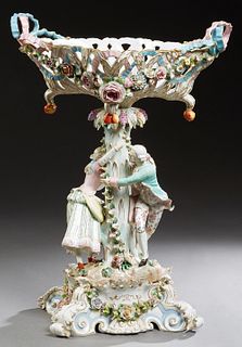 Large Meissen Polychromed Porcelain Figural Centerpiece, c. 1870, with a pierced relief floral basket on a figural support of lovers cavorting around 