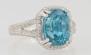 Lady's 14K White Gold Dinner Ring, with a 7 carat oval blue zircon atop an undulating border of small round diamonds, over an undulating diamond mount