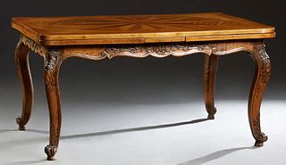 Louis XV Style Carved Mahogany Draw Leaf Dining Table, early 20th c., with a geometric inlaid top and leaves, above a floral and leaf carved shaped sk