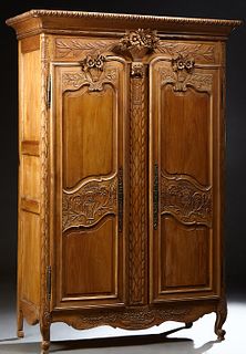 French Provincial Carved Walnut Marriage Armoire, 19th c., the rounded corner and edge crown over a large floral basket, flanked by double floral carv