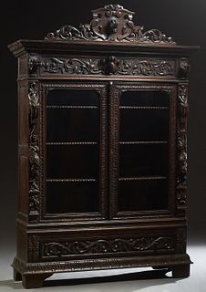 French Henri II Style Carved Oak Bookcase, c. 1880, the pierced shield crest with a central high relief wolf's head, over a frieze with two relief dog