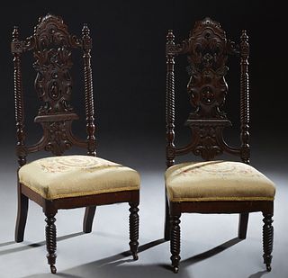 Pair of Continental Carved Mahogany High Back Hall Chairs, late 19th c., the arched pierced crest flanked by finials, above a pierced floral carved ba