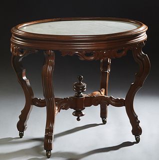 American Carved Walnut Oval Marble Top Center Table, c. 1880, with an inset white marble top over a skirt with applied leaf and floral carving, on cab
