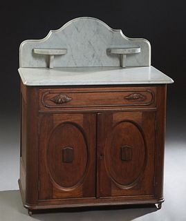 American Carved Walnut Marble Top Washstand, 19th c., with an arched white marble back splash with two candle stands, over an ogee edged white marble,