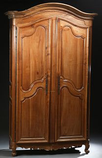 Louis XV Style Carved Cherry Armoire, c. 1800, the stepped arched crown over double arched panel doors with long iron escutcheons and fiche hinges, on