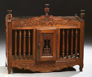 French Provincial Carved Walnut Panettiere, 19th c., the arched finialed crown over a central pierce carved door, flanked by turned spindles and like 