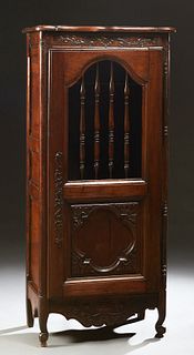 French Provincial Carved Walnut Bonnetiere, 19th c., the serpentine top over a single door with a spindled upper panel over a carved lower panel, long