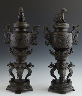 Pair of Japanese Bronze Censers, c. 1900, the lids with Foo lion handles over baluster sides with relief garden scenes with dragon handles, on four dr