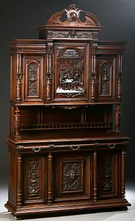 French Provincial Carved Walnut Buffet a Deux Corps, c. 1880, the broken arch crest over a stepped crown above a setback central cupboard door with a 