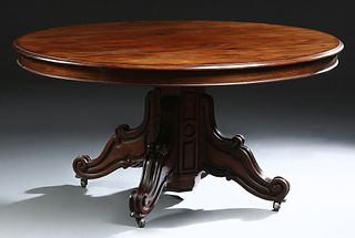 French Carved Mahogany Dining Table, c. 1870, the rounded edge oval top on an octagonal support on four reeded splayed scrolled feet, opening to accep