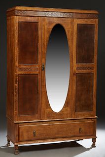 English Carved Oak Armoire, c. 1930, the sloping stepped edge crown over a central oval beveled mirror door, flanked by dark oak panels with central a