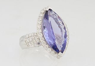 Lady's Platinum Dinner Ring, with an 8.22 carat marquise tanzanite atop a conforming border of round diamonds, the tapered shoulders of the band with 