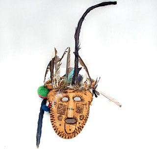 Máscara wixárika. México. Siglo XX. Elaborada en madera pirograbada. Decorada con plumas, ojos de Dios miniatura, borlas y cuentas.