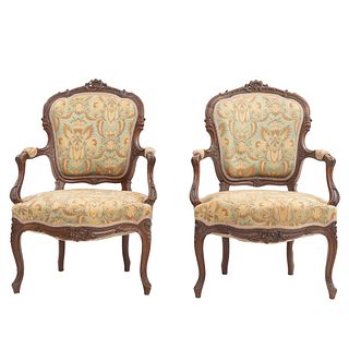 Par de sillones. Francia. Siglo XX. En talla de madera de nogal. Con respaldos y asiento en tapicería floral.