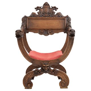 Curul. Francia. Siglo XX. En talla de madera de nogal. Con respaldo semiabierto y asiento en tapicería color bermellón.