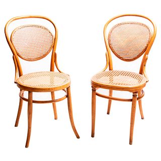Par de sillas. Siglo XX. Estilo austriaco. En talla de madera. Con respaldos semiabiertos y asientos de bejuco, fustes lisos.