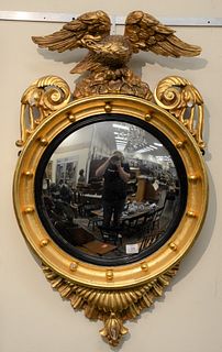 Large Federal Carved and Giltwood Convex Mirror, having eagle with spread wings perched on rockery, reeded ebonized slip above leaf ...
