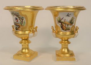 Pair Paris Porcelain Urns, each with overall gilt decoration and panels of Asian hunters, handles with unglazed porcelain masks, 19t...