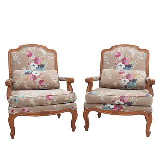 Par de sillones. Siglo XX. En talla de madera. Con respaldos cerrados y asientos con cojínes en tapicería floral color beige.
