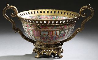 Large Chinese Gilt Bronze Mounted Famille Rose Center Bowl, 20th c., with a pierced bronze rim with two scrolling handles, on a pier...
