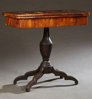 American Classical Carved Walnut Games Table, 19th c., the swiveling top over open storage, on a baluster urn form support, to a qua...