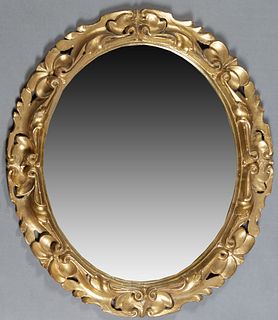 American Carved Giltwood Oval Overmantel Mirror, 19th c., the pierced frame with relief leaf and floral carving around the oval plat...
