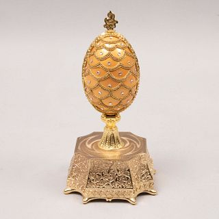Huevo decorativo. Siglo XX. A la manera de Carl Fabergé. En metal y resina. Color dorado. Con figura de la Sagrada Familia al interior.