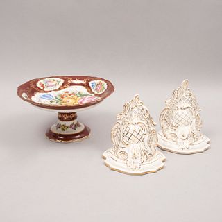 Lote de centro de mesa y par de peanas. Alemania e Inglaterra. Siglo XX. Elaboradas en porcelana y cerámica vidriada.