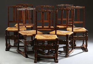 Set of Eight Carved Oak Spanish Rush Seat Dining Chairs, 20th c., the arched leaf carved back with lappet carved vertical splats, to a trapezoidal rus