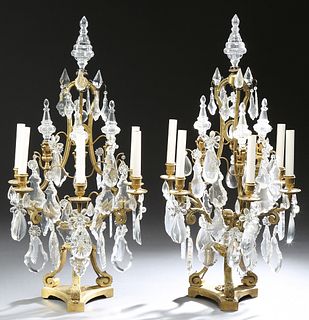 Pair of Gilt Bronze and Crystal Five Light Girandoles, 20th c., of basket form, mounted with crystal spires and numerous pendalogue prisms, and prism 