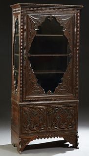 French Provincial Highly Carved Oak Vitrine, late 19th c., the stepped crown over a floral carved shaped glazed door flanked by like sides, on a base 