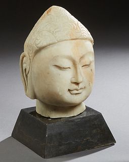 Carved Marble Head of Buddha, 19th c. or earlier, presented on a sloping black marble plinth, Head- H.- 12 in., W.- 7 in., D.- 8 in., Plinth- H.- 3 1/