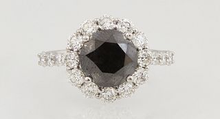 Lady's 14K White Gold Dinner Ring, with a circular 3.22 ct. black diamond, atop a border of round white diamonds, the shoulders of the band also mount