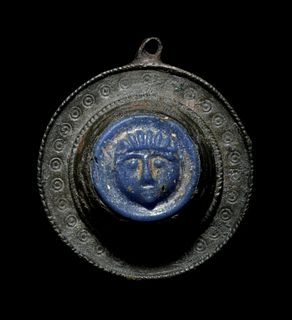 A Romano-Celtic Bronze and Blue Glass Fibula with a Mask
Diameter 1 1/4 inches.