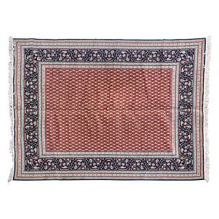 Tapete. Siglo XX. En fibras de lana. Decorado con motivos orgánicos y florales sobre fondo rojo con cenefa azul.