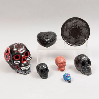 Lote mixto de 7 piezas. México. Siglo XX. Elaborados en barro negro y cerámica. Consta de: 5 cráneos, alhajero y platón.