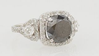 Lady's 14K White Gold Dinner Ring, with a 4.87 carat cushion cut black diamond, atop a border of small round white diamonds, flanked by diamond mounte