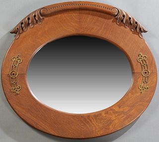 American Carved Oak Oval Overmantel Mirror, late 19th c., with a leaf and bead carved crest over an oval wide beveled plate, flanked by two pierced br