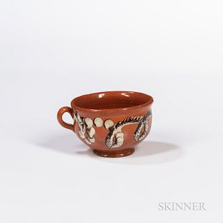 Redware Porringer or Mug with Slip Cable Decoration, 19th century, with flaring rim, loop fingerhold, and turned foot, ht. 2 3/4, bowl