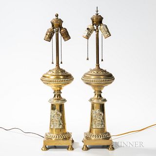 Pair of Brass Oil Lamps: "American Progress" and "Manifest Destiny," mid-19th century, the reservoirs above columnar bases with applied