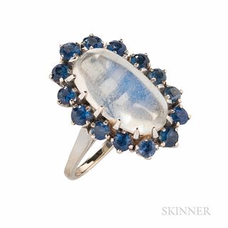 14kt White Gold, Moonstone, and Sapphire Ring, the oval cabochon moonstone measuring approx. 16.40 x 8.70 x 6.70 mm, framed by circular